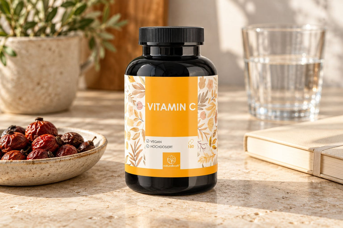 NATURALKRAFT Vitamin-C-Kapseln neben getrockneten Hagebutten und einem Wasserglas.
