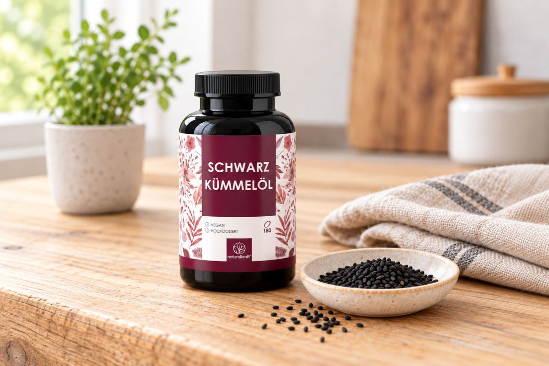 NATURALKRAFT Schwarzkümmelöl-Kapseln mit Schwarzkümmelsamen auf einem Holztisch